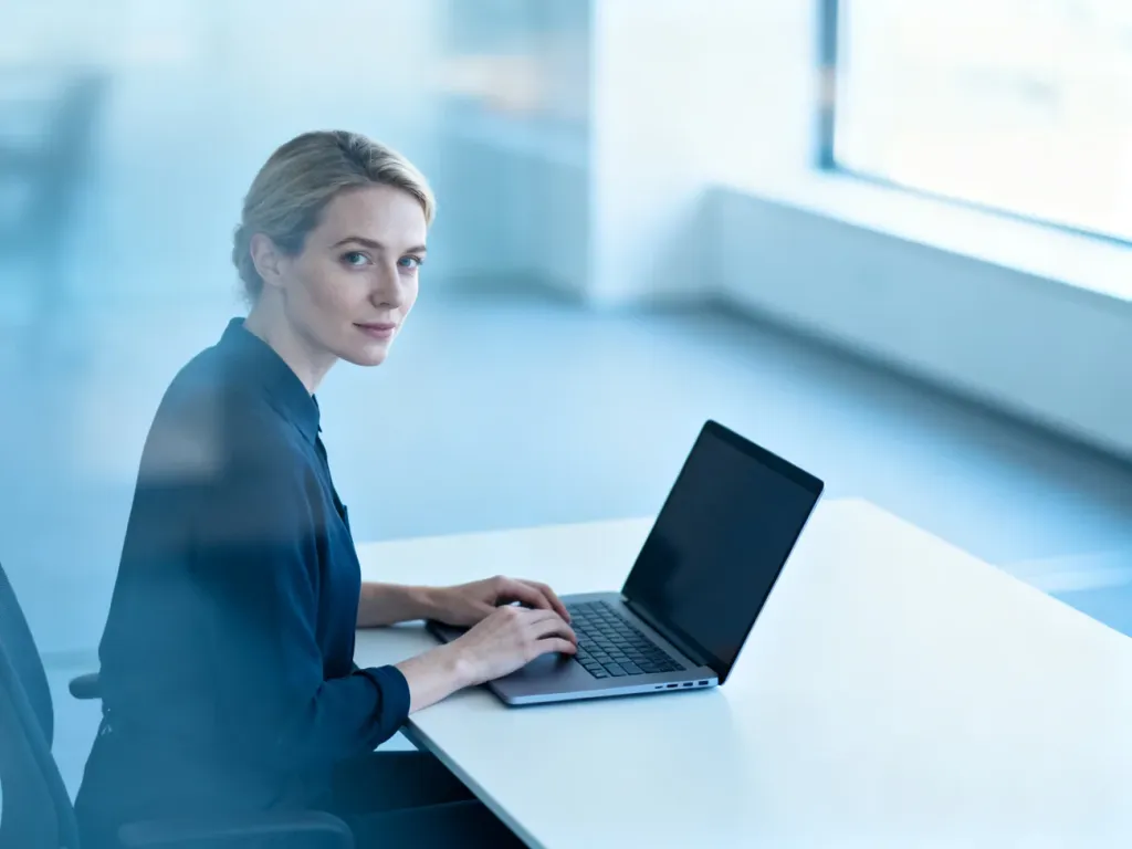 Kobieta pracująca przy laptopie w nowoczesnym biurze, symbolizująca łatwy dostęp do systemu Ebiuro Symfonia.